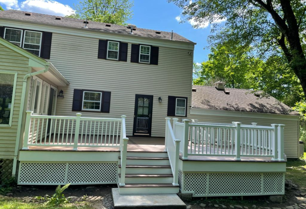 Custom elevated back deck with white railing, courtesy of Lasting Construction LLC