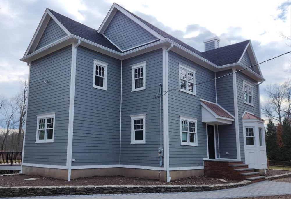 Classic gray siding, new roof, and hardscaping on a new construction home, courtesy of Lasting Construction LLC.